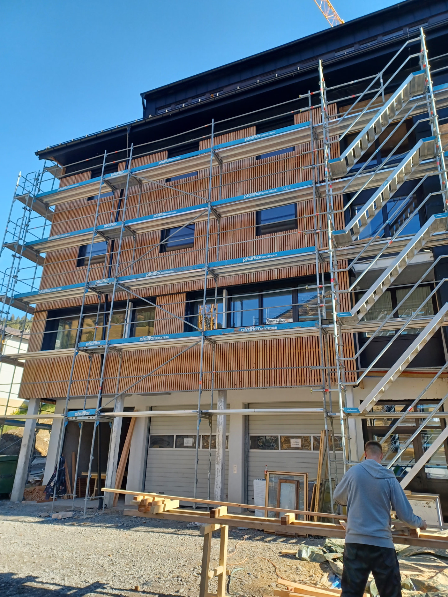 Holzfassade in Montage hinter einem Baugerüst in Vorarlberg